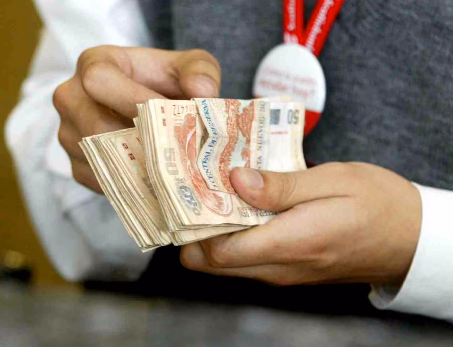 Un trabajador del Banco de la Nación con un fajo de billetes | Foto: Andina