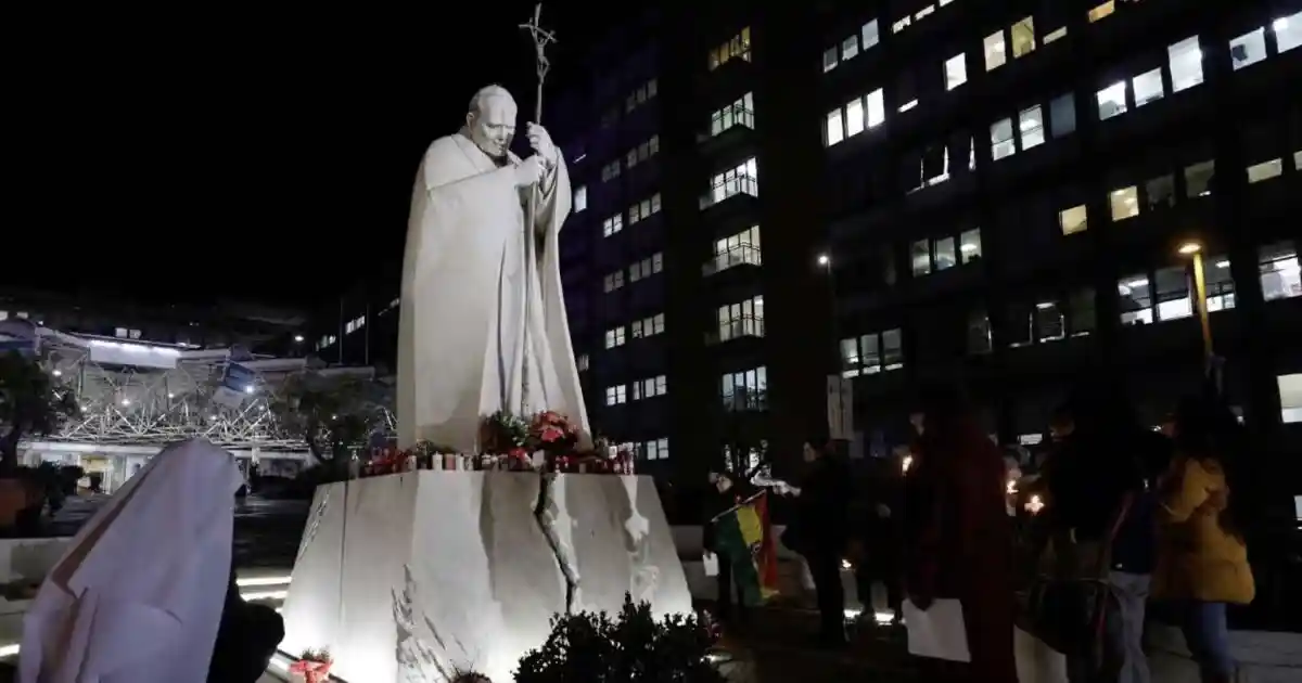 Fieles rezan frente a la estatus de San Juan Pablo II, en el Policlínico Gemelli de Roma donde permance hospitalizado el papa Francisco | Foto: Vatican News
